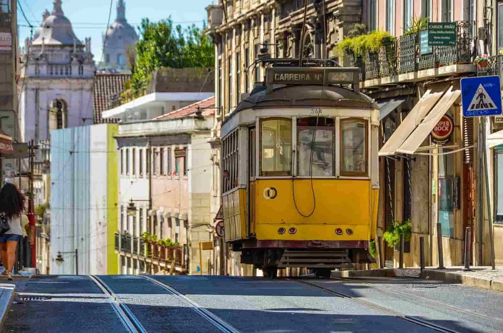A Lisbon yellow trolley is driving down a city street.