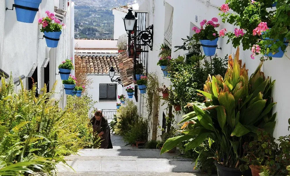 A woman is walking down a narrow alleyway in Mijas pueblo