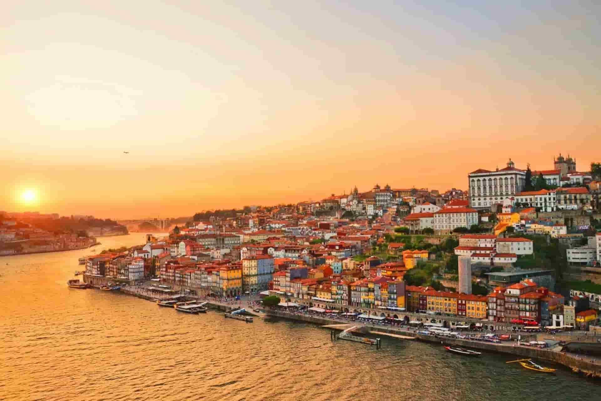An aerial view of Porto along a river at sunset.