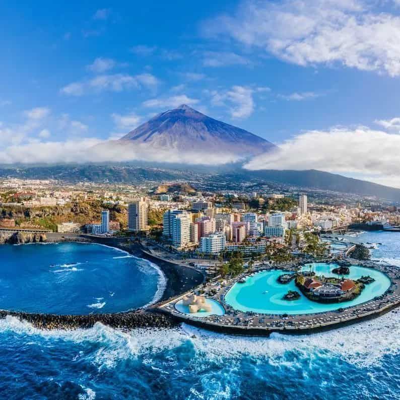 An aerial view of Tenerife in the middle of the ocean with a volcano in the background.