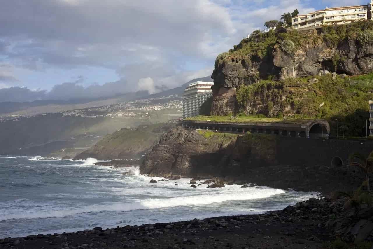 A cliff overlooking a body of water with a building in the background
