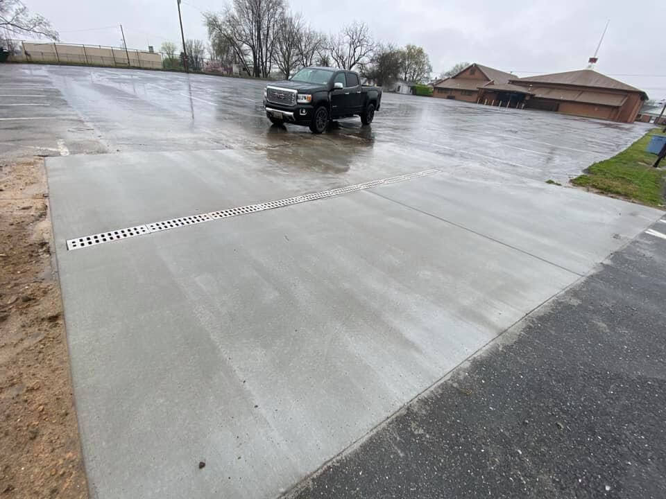 An image of a concrete parking lot with a black car