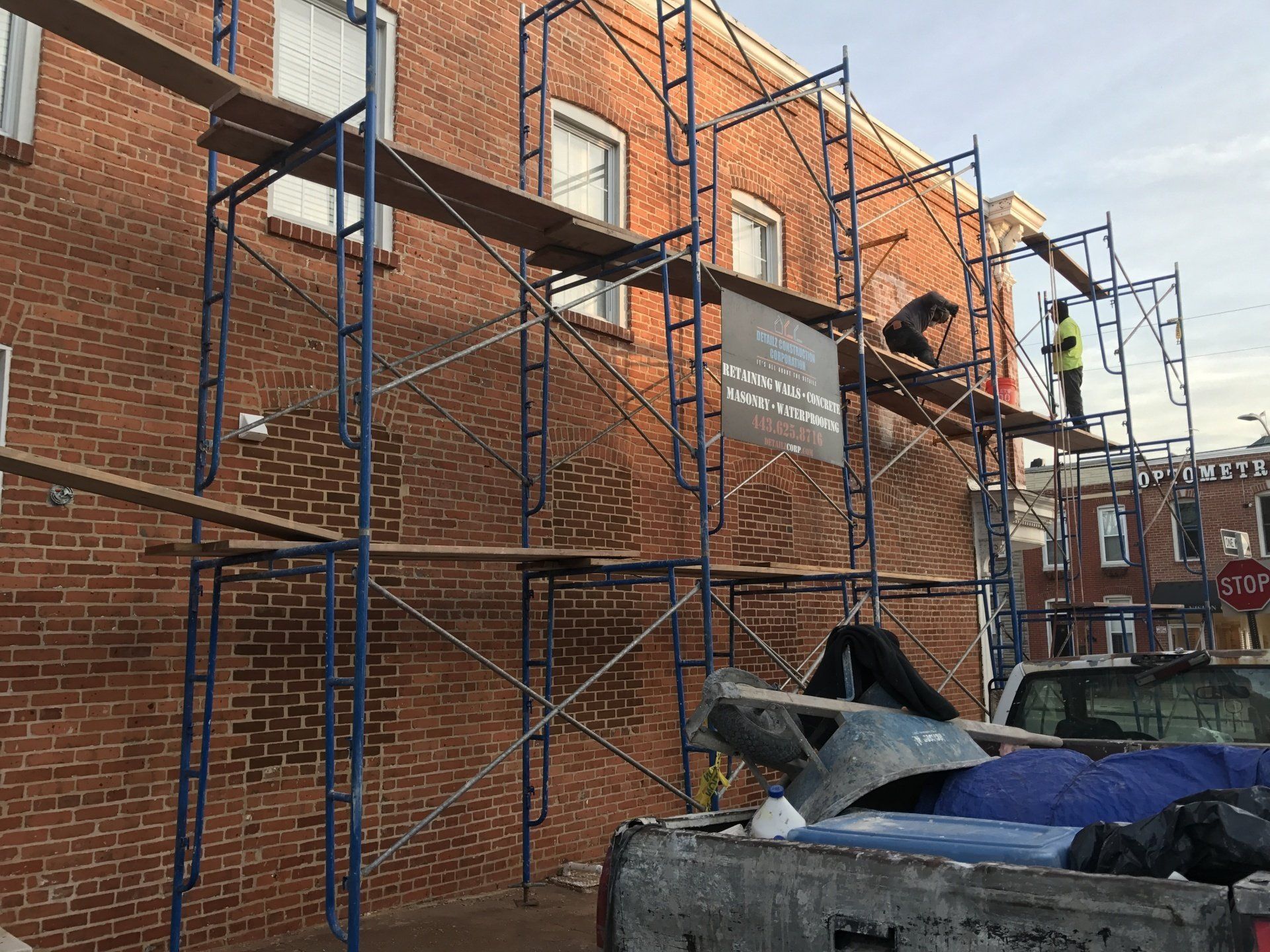 Unfinished brick style building with 2 construction worker