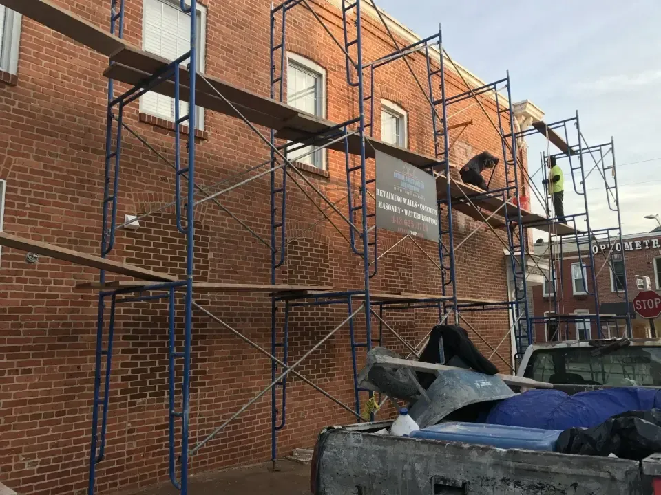 Workers providing exterior wall repair services on scaffolding