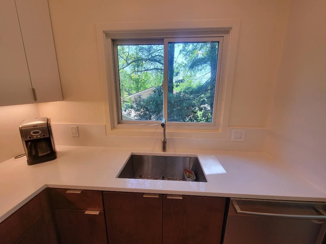 Kitchen with a stainless steel sink, window, and cabinets; coffee machine on the counter.