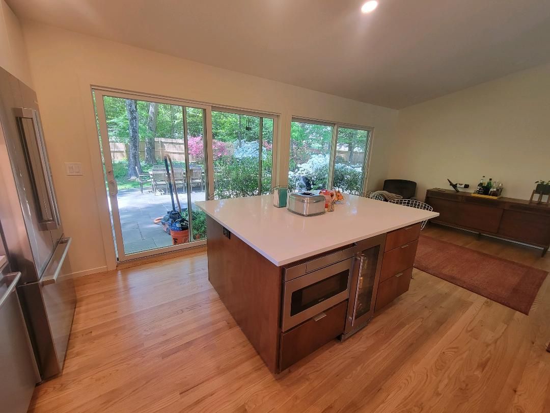 Kitchen with island, wood floors, and large windows overlooking a garden.