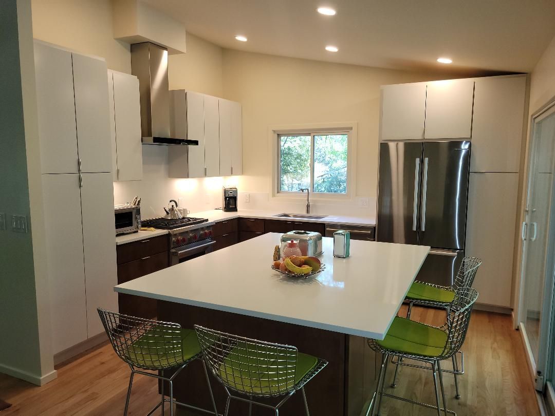Modern kitchen with white cabinets, brown island, and stainless steel appliances.