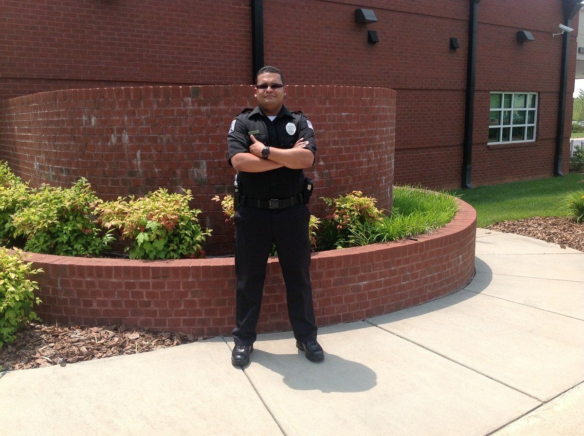 A security guard standing with their arms crossed and protecting a building 
