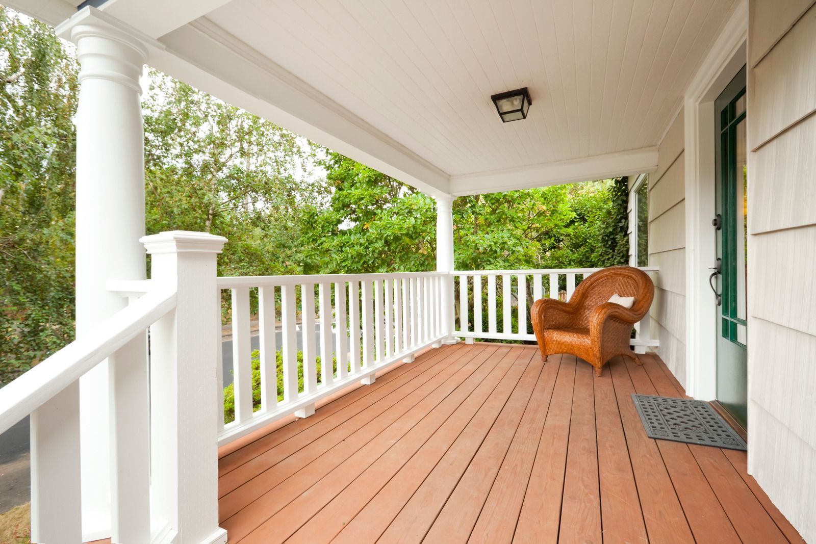 A porch with a chair on it and a white railing