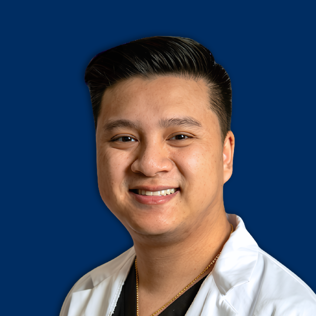 Smiling man in a white coat against a solid blue background