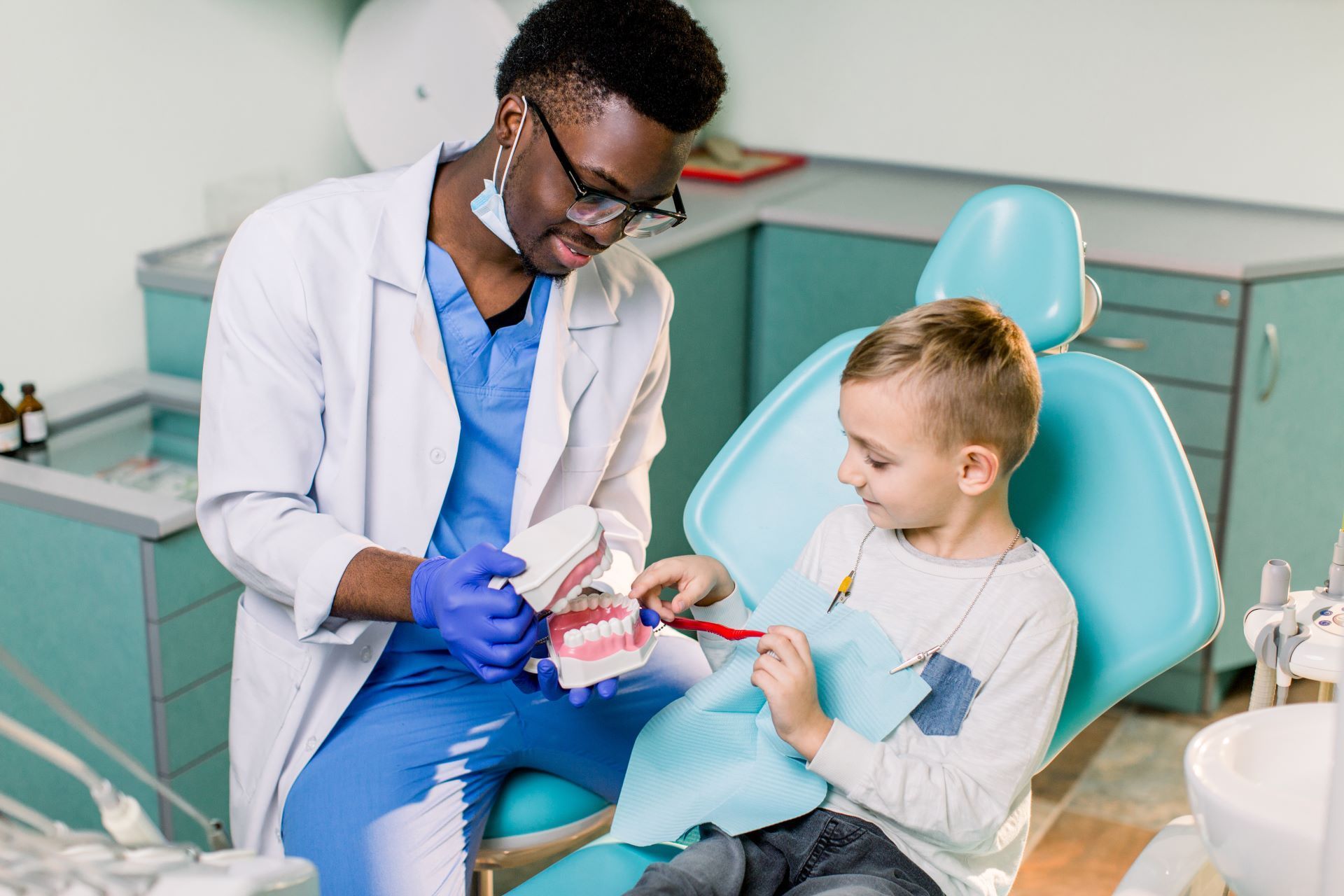 Dentist showing a young patient a model of teeth in a bright dental clinic