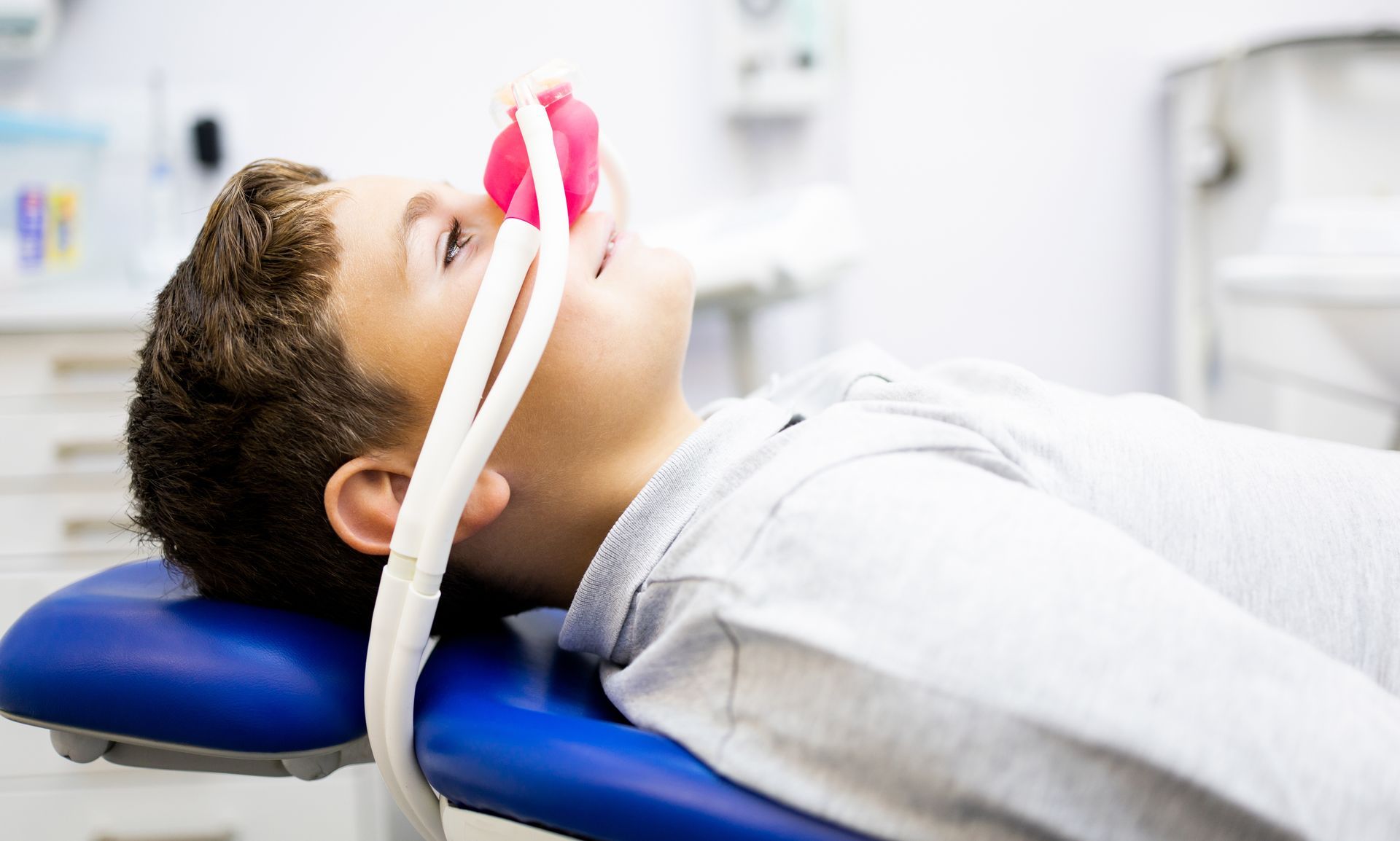 Patient lying on a dental chair wearing a breathing mask during treatment