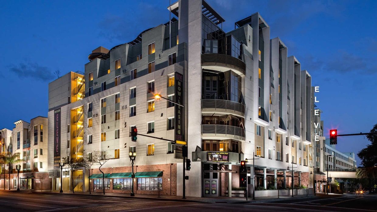 Hotel building at night, lit with warm lights. White and tan exterior, street lights in front.
