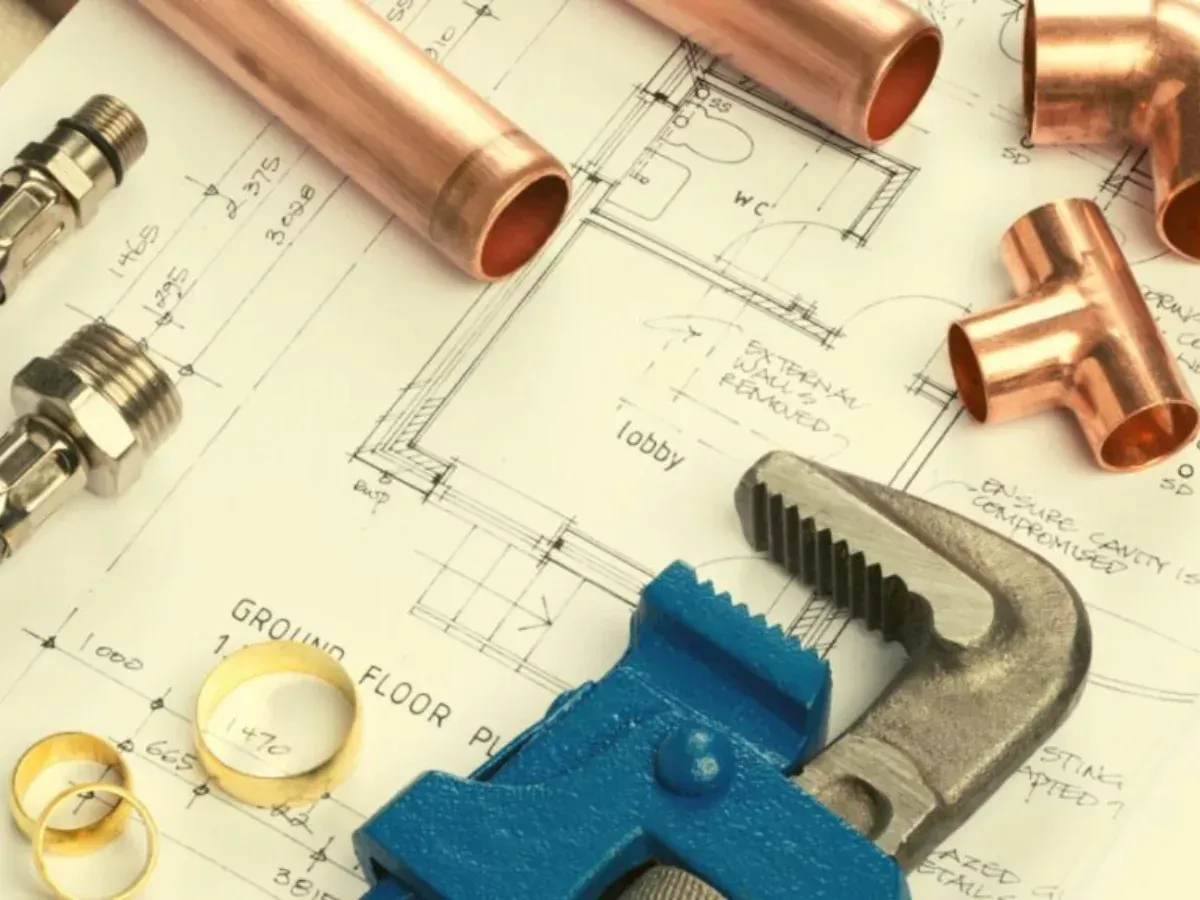 Copper pipes and a wrench on top of a floor plan