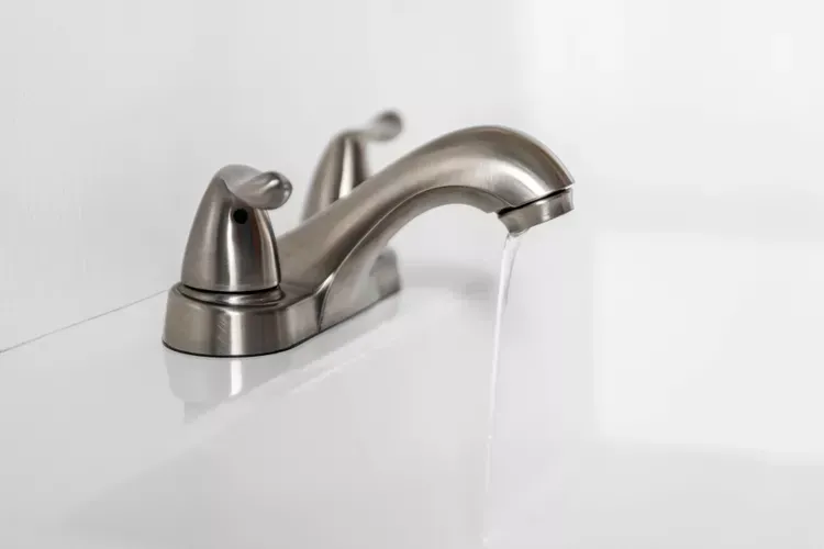 A close up of a bathroom sink faucet with water running out of it. A close up of a bathroom sink faucet with water running out of it.