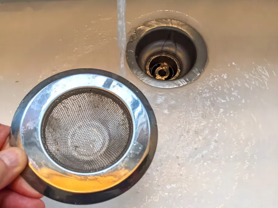 A drain with a drain stopper being put in to prevent clogs. A drain with a drain stopper being put in to prevent clogs.