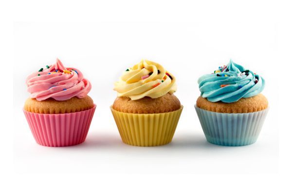 three colorful cupcakes with frosting and sprinkles on a white background
