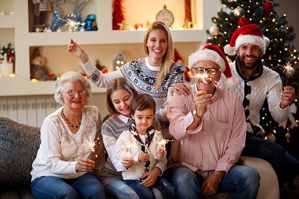 a family is sitting on a couch holding sparklers in front of a christmas tree .