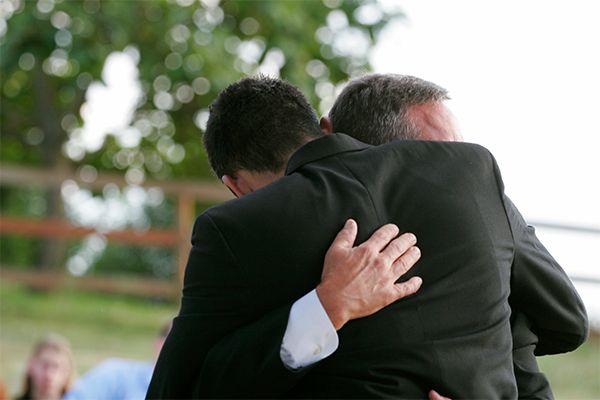 a man in a suit is hugging another man in a suit .