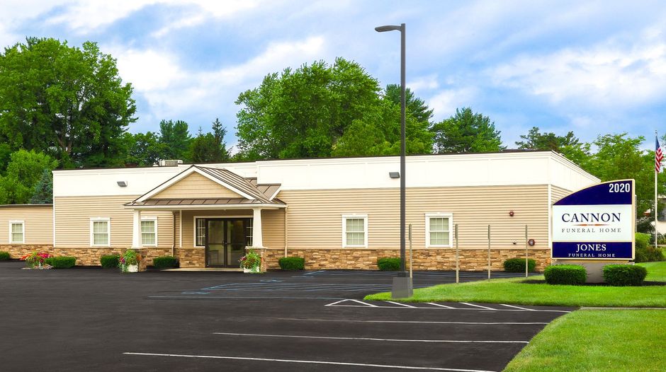 A man in a suit and tie is standing in front of a cannon funeral home.