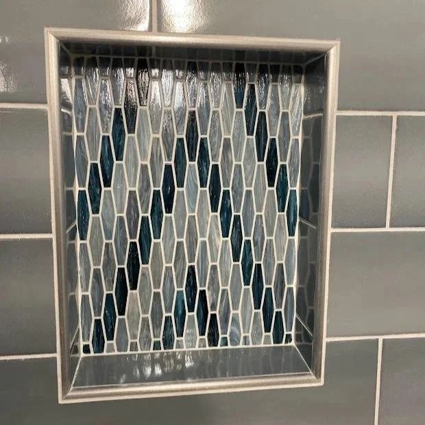 Tile shower niche with blue and gray mosaic tile design.