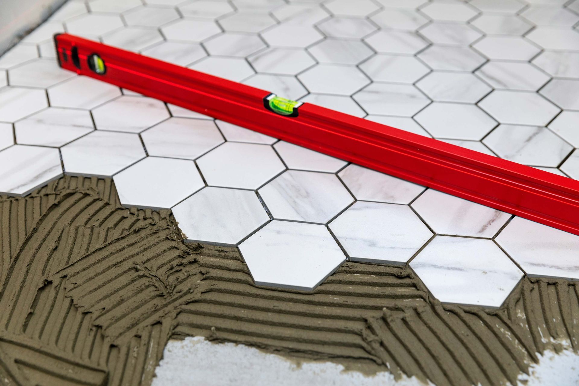 Red level on hexagon tile, partially laid on mortar.