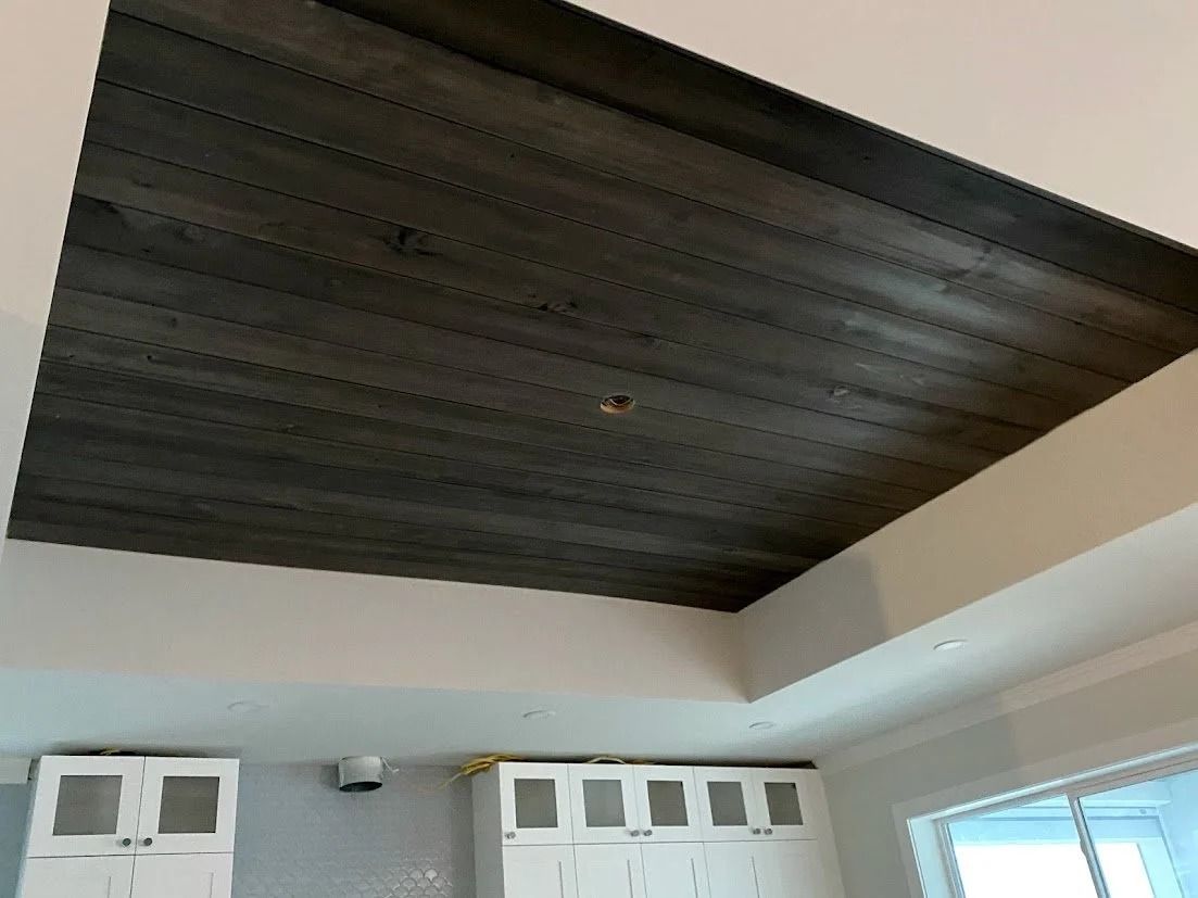 Gray wood plank ceiling with white trim and cabinets below.