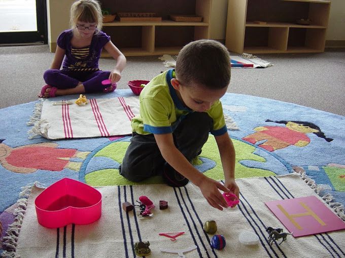 A boy and a girl are playing with toys on a rug