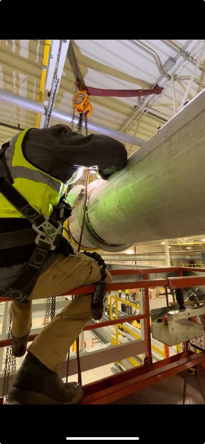 A man is working on a pipe in a factory.