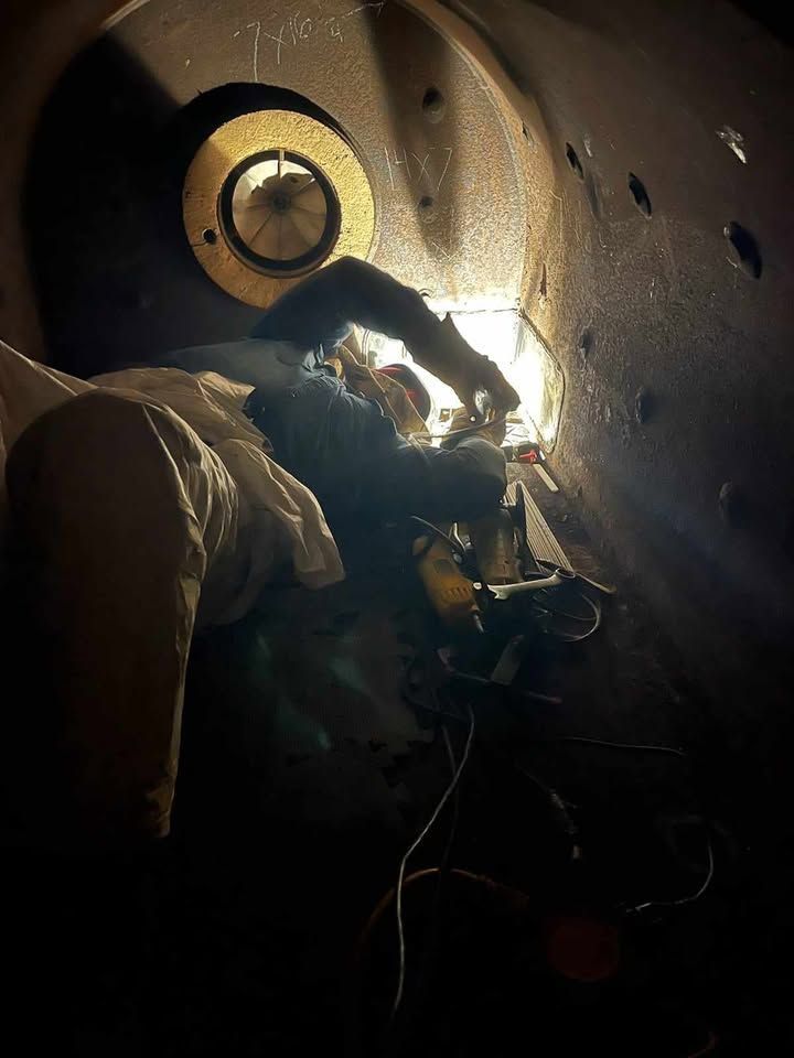 A person is welding a pipe in a dark room