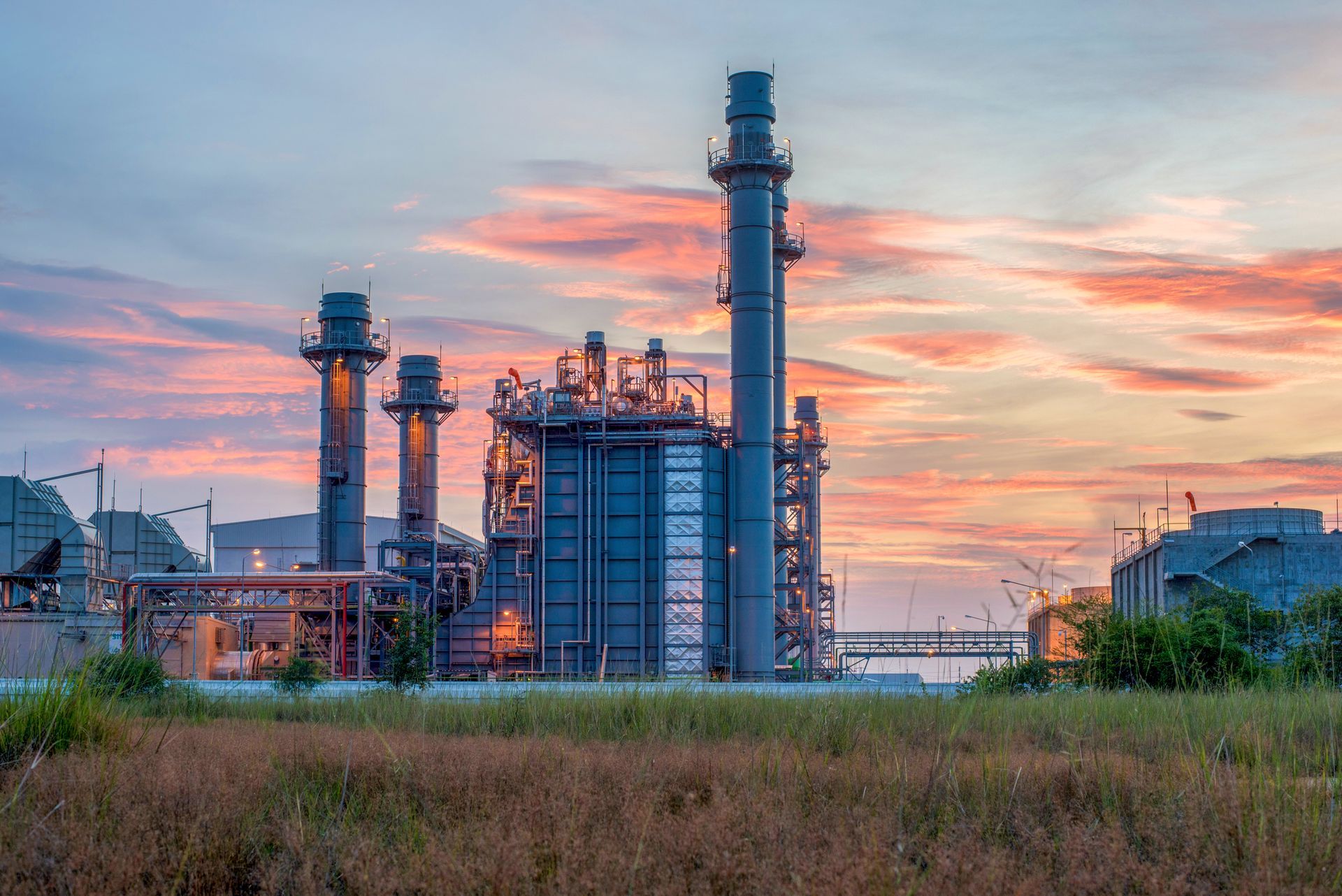 A large industrial plant with a sunset in the background.