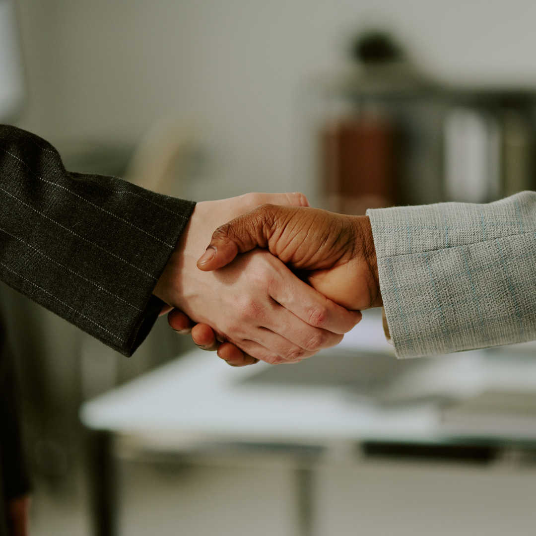 Deux personnes en tenue professionnelle se serrent la main dans un bureau.