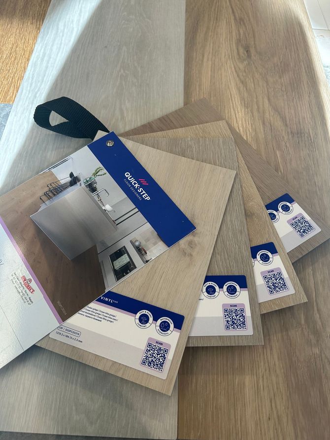 Un nuancier d'échantillons de revêtements de sol en vinyle de luxe dans des tons de gris, beige et marron, comportant les codes QR des marques de produits.