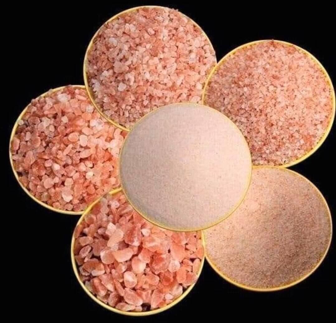 Five round bowls of pink and beige granular crystals arranged in a flower pattern on a black background