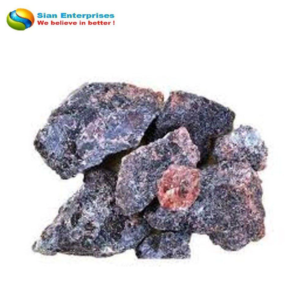 Pile of dark rough rocks with reddish mineral patches on a white background