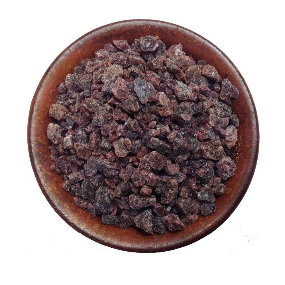A small wooden bowl filled with dark raisins on a white background