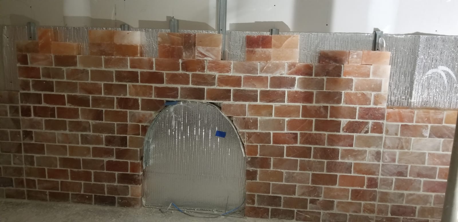 Brick-patterned cardboard castle wall with a central arched opening and silver foil details.
