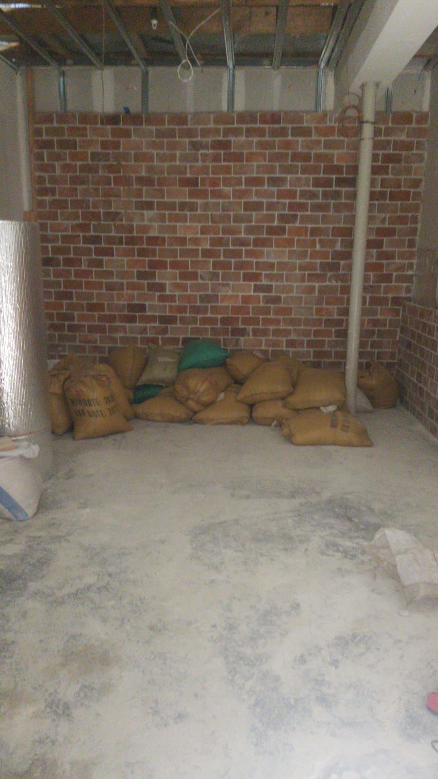Brick storage room with sacks stacked along the back wall and a concrete floor