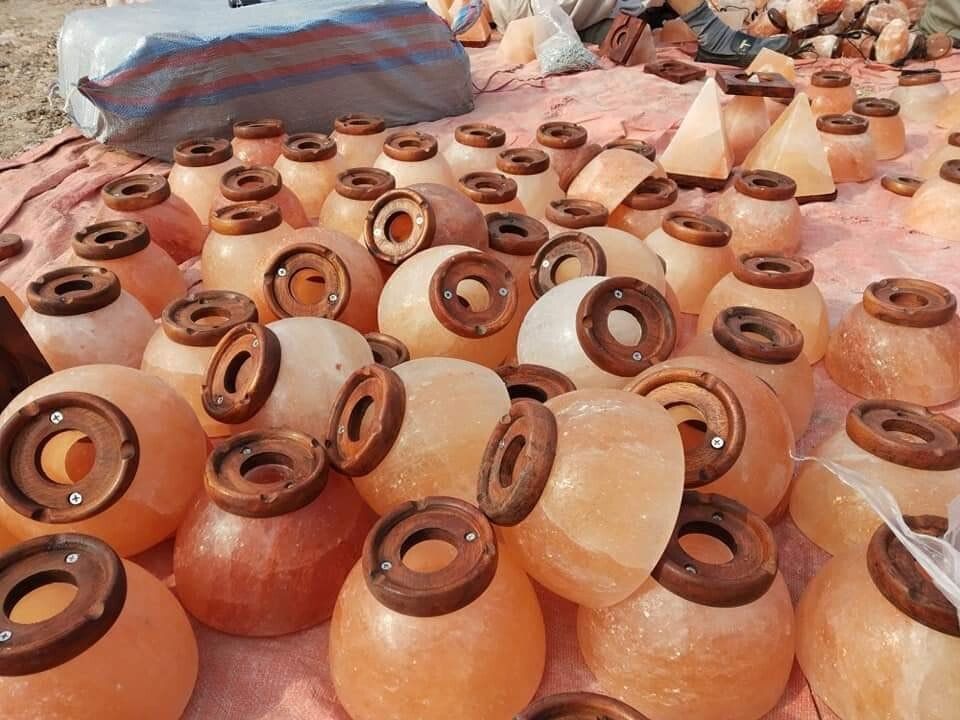 Rows of unglazed clay pots with brown lids displayed at an outdoor market stall.