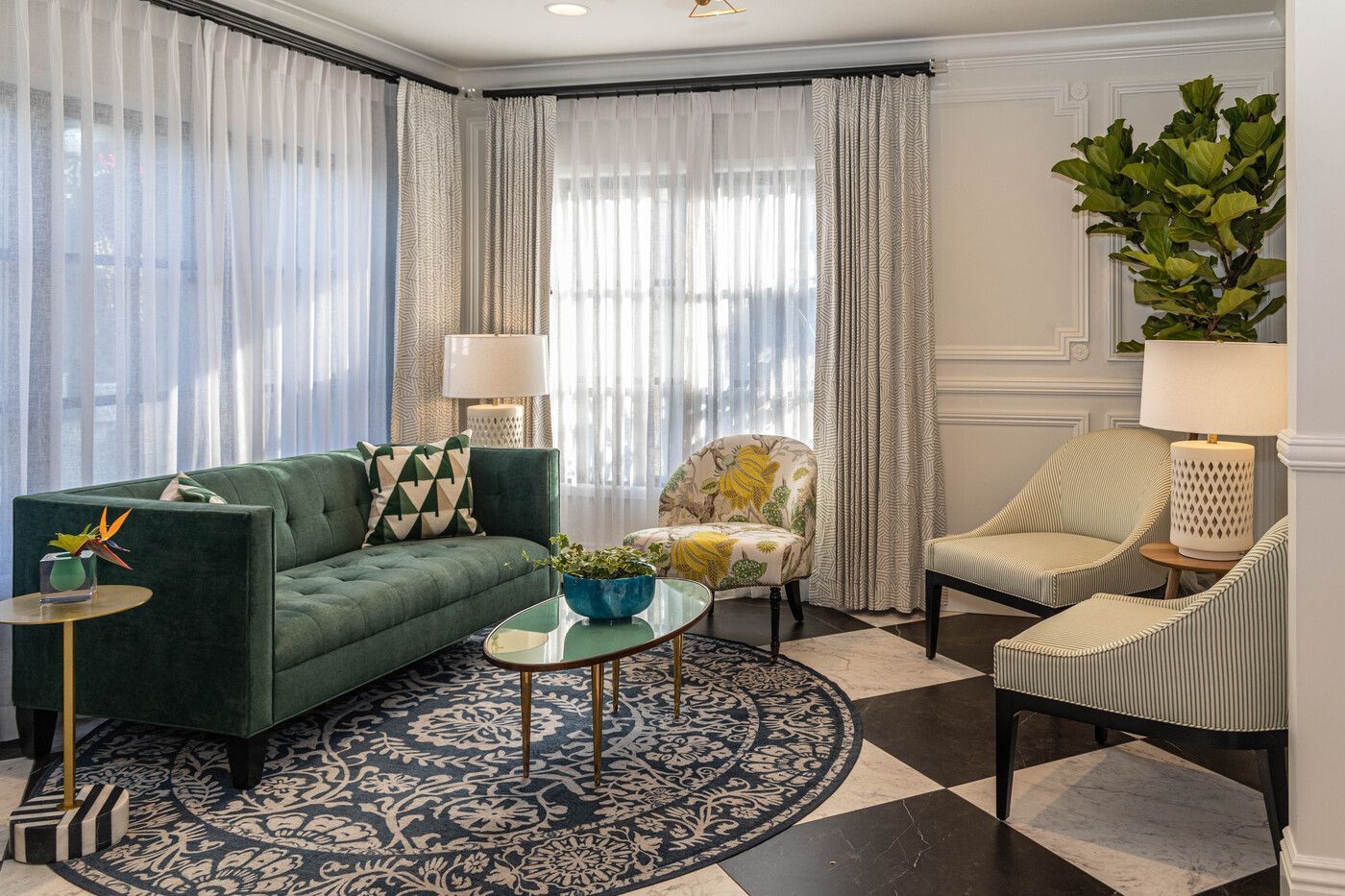 A living room with a green couch , two chairs , a coffee table and a rug.