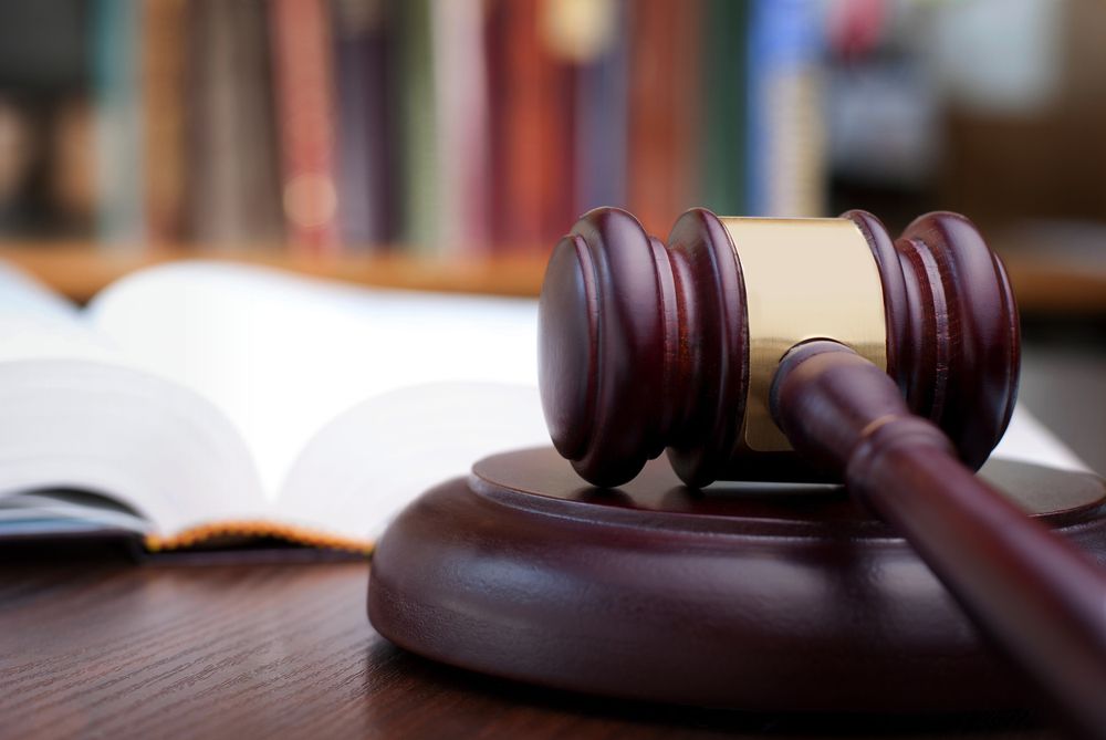 A Wooden Judge's Gavel Is Sitting On A Wooden Table Next To An Open Book — Spencer Lawyers In Gosford, NSW