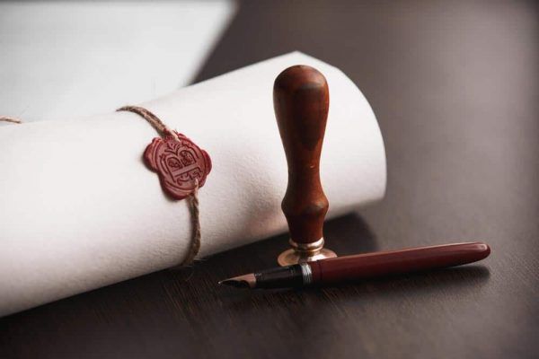 A Roll Of Paper With A Wax Seal And A Pen On A Table — Spencer Lawyers In Gosford, NSW