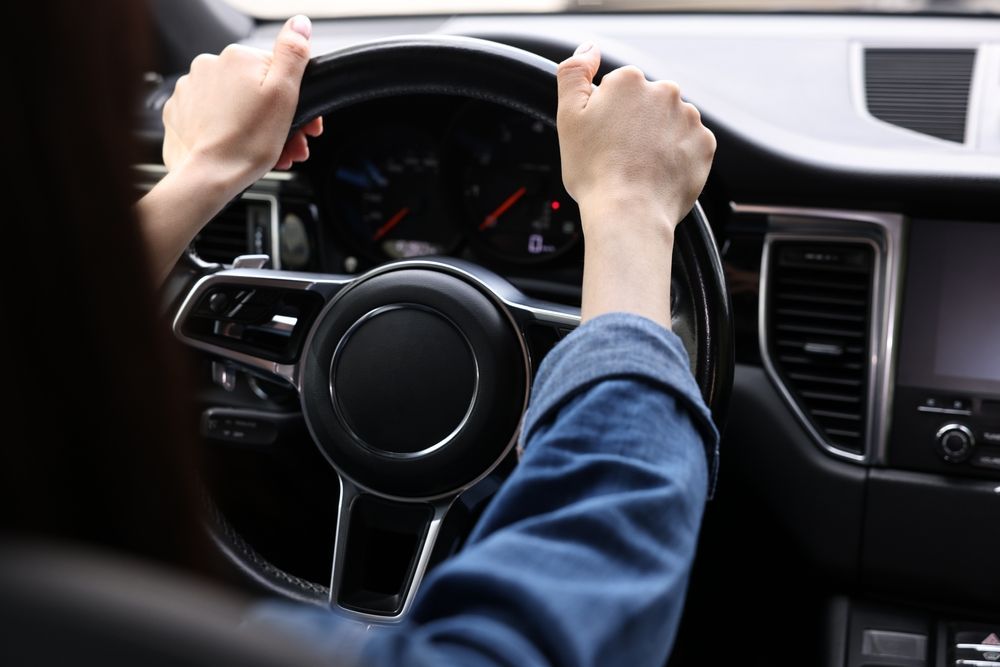 A Man In A Suit Is Driving A Car — Spencer Lawyers In Gosford, NSW