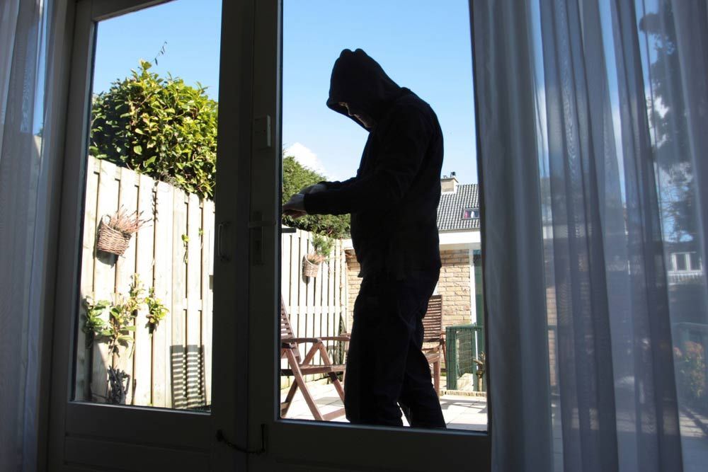 A Man In A Hooded Jacket Is Looking Out Of A Window — Spencer Lawyers In Gosford, NSW