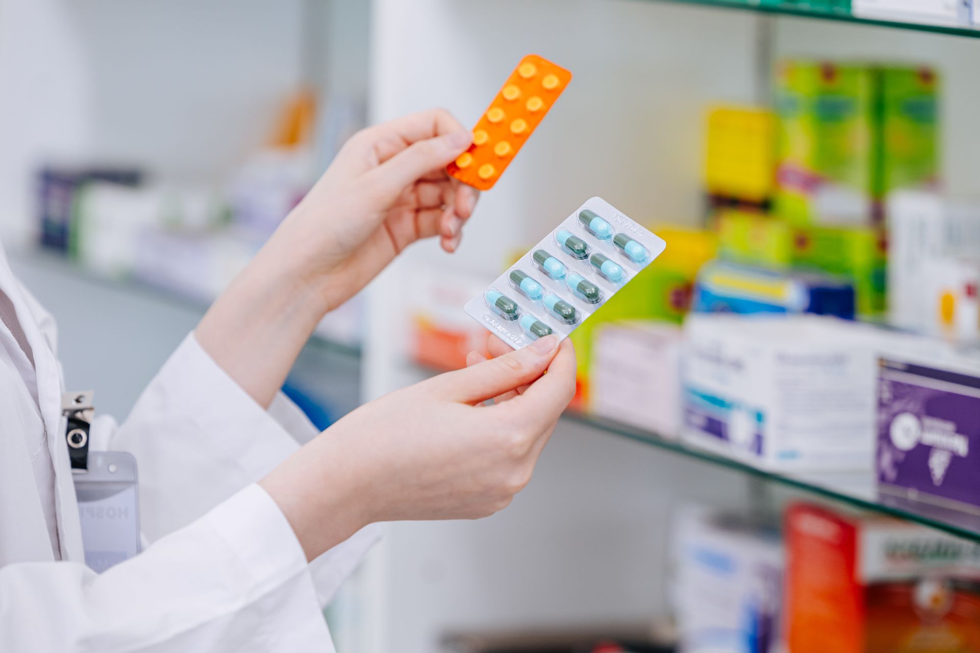 Hands holding two blister packs of pills in a pharmacy aisle