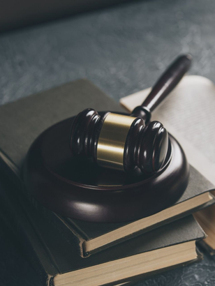 Gavel on a wooden block atop a stack of books, in a dim setting.