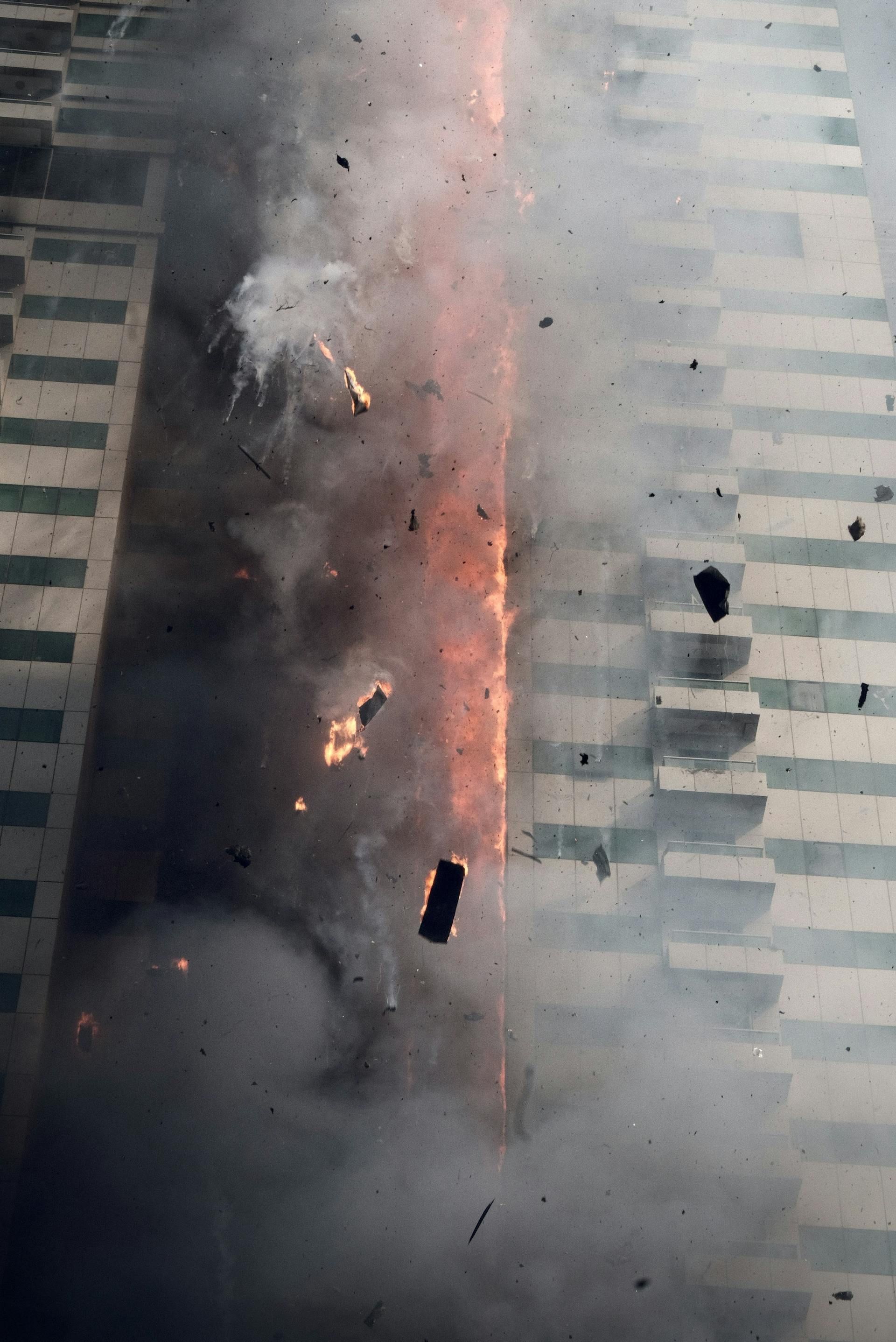 Building facade with a fiery explosion, smoke, and debris.