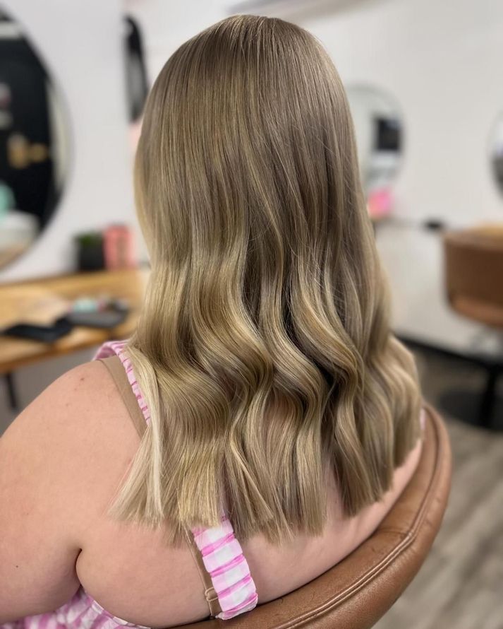 A Woman With Long Blonde Hair Is Sitting In A Chair In A Salon — Freedom Hairdressing In Casino, NSW
