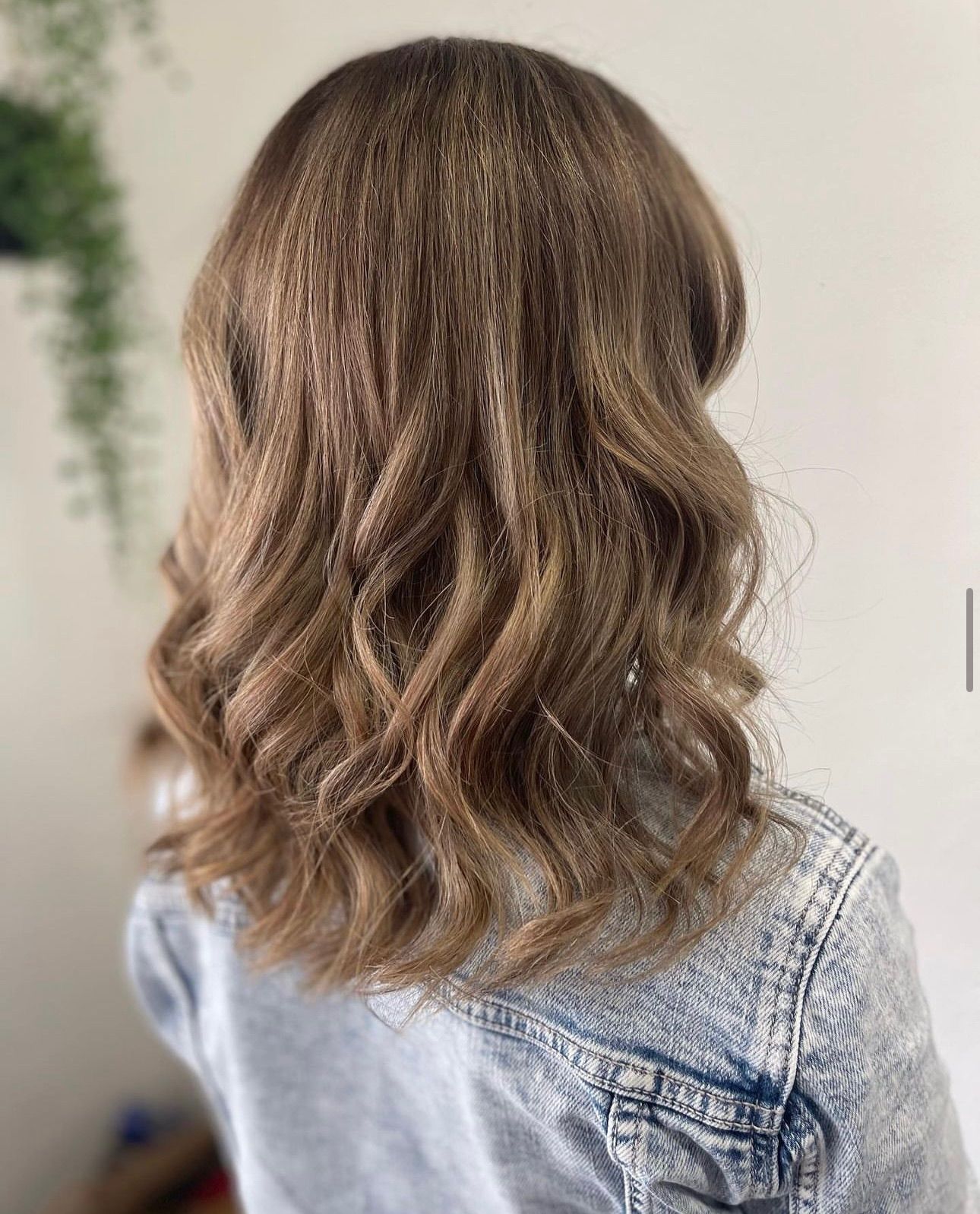 A Woman With Long Blonde Hair Is Sitting In A Chair In A Salon — Freedom Hairdressing In Casino, NSW