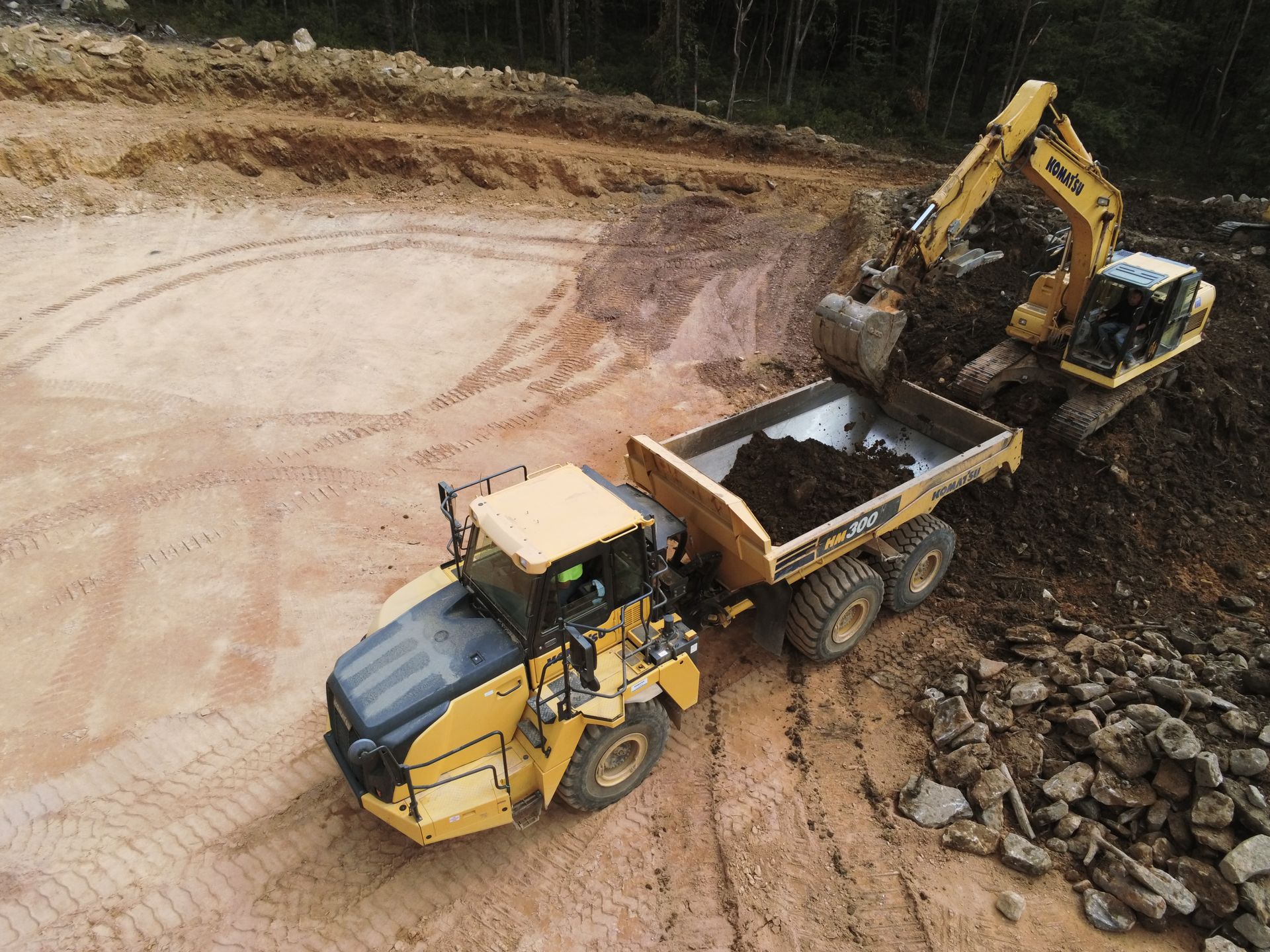 An aerial view of a dump truck and an excavator in a Kobalt construction site.